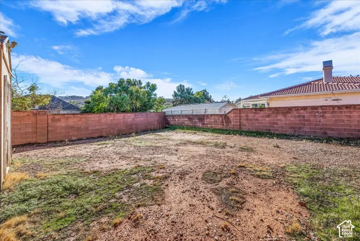 Expansive backyard featuring a masonry block wall perimeter, native landscaping, and a mountainous backdrop