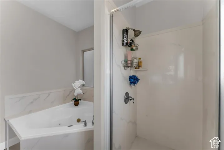Corner soaking tub with integrated surround, glass-enclosed shower, and polished chrome fixtures