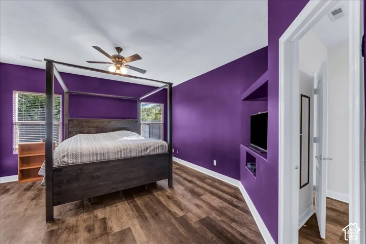 Room featuring wood-finish flooring, a built-in recessed media niche, and a ceiling fan with light fixture