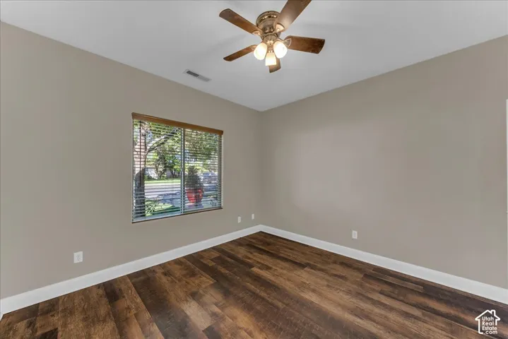 Room featuring wood-finish flooring, neutral wall paint, a multi-blade ceiling fan with integrated lighting, and a window with horizontal blinds
