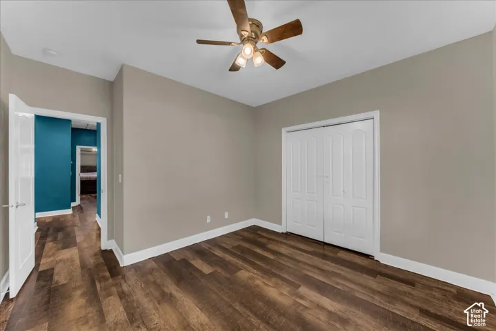 Room featuring wood-finish flooring, a ceiling fan with integrated lighting, and a closet with white paneled bi-fold doors