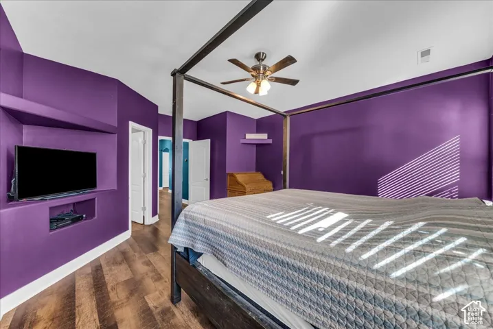 Wood-finish flooring, built-in recessed wall shelving, and a ceiling-mounted light fixture with fan