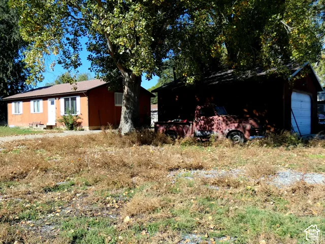 Single-story residence featuring wood-tone exterior siding, a shingled roof, and an attached garage with a roll-up door