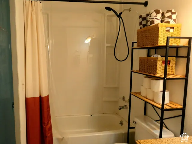 Tub-shower combination featuring a white molded surround, matte black rainfall showerhead, integrated shelving, and metal hardware