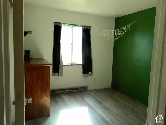 Room featuring wood-finish flooring, a single window, and a painted accent wall
