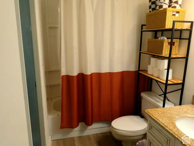 Bathroom featuring a vanity with a light-toned countertop, integrated basin, tub-shower combination, and wood-finish flooring
