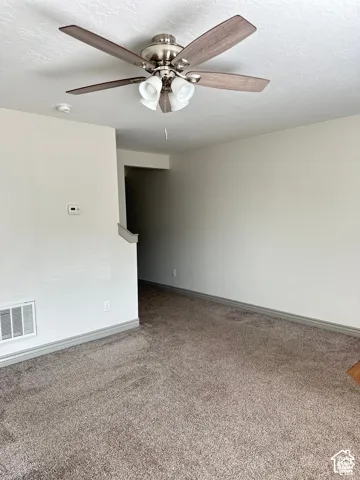 Room featuring neutral wall tones, wall-to-wall carpeting, and a ceiling-mounted fan with integrated multi-bulb light fixture