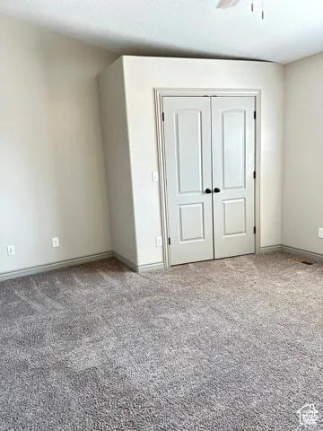 Neutral-toned interior featuring vaulted ceilings, wall-to-wall carpeting, and double-panel closet doors with matte black hardware