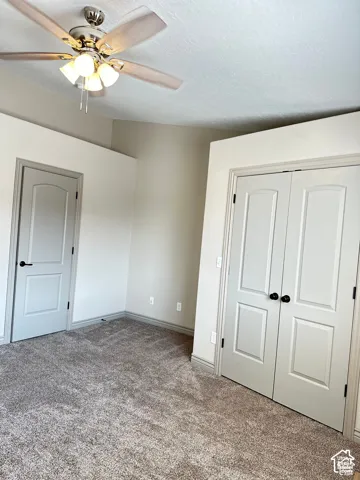 Vaulted ceilings, neutral carpeting, multi-panel doors with matte black hardware, and a ceiling fan with integrated lighting