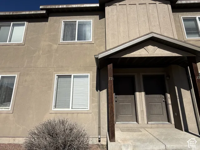 Two-story exterior featuring stucco siding, vertical board-and-batten accents, sliding windows, and a covered entryway supported by wooden posts