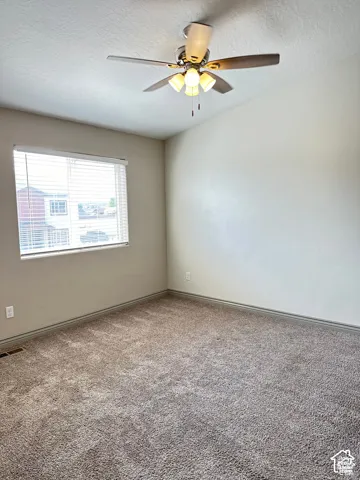 Neutral-toned walls, high ceilings, ceiling fan with multi-light fixture, and carpeted flooring