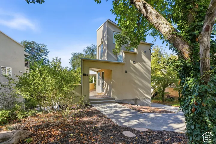Modern multi-level exterior featuring stucco siding, geometric architectural lines, a covered entryway, and a concrete driveway