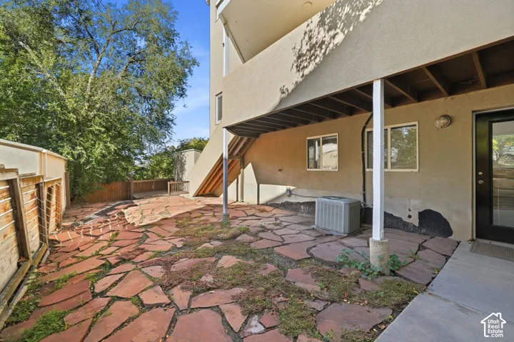 Flagstone patio featuring a concrete walkway, wood-panel fencing, and a covered ground-level exterior space
