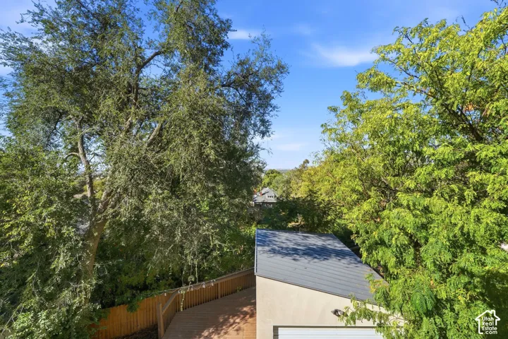 Exterior structure featuring a metal roof, stucco siding, wood decking, and mature trees