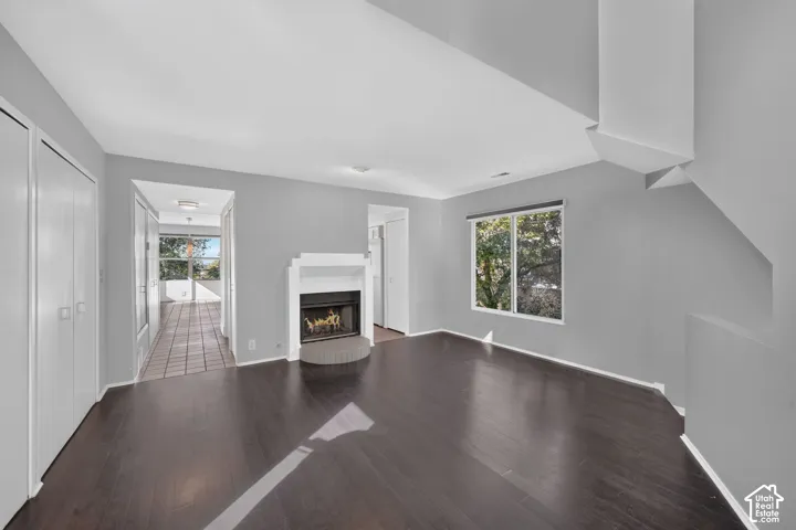 Living space featuring dark wood-finish flooring, high ceilings, built-in fireplace with a white mantel, and a dual-pane window