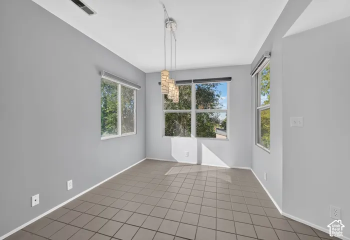 Neutral-toned interior space featuring ceramic tile flooring, three large windows with roller shades, and a triple-pendant light fixture