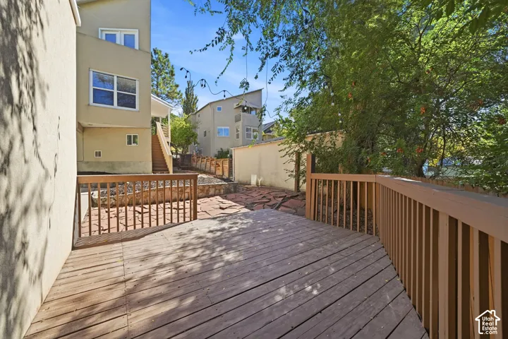 Raised wood deck featuring vertical wood balusters, complemented by a stone-paved patio and tiered landscaping with wood retaining walls