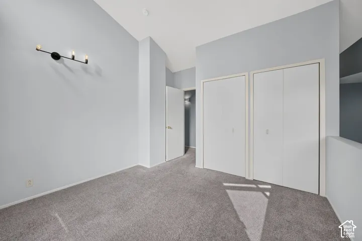 Vaulted ceilings, neutral carpeting, dual bi-fold closets, and three-bulb wall-mounted fixture
