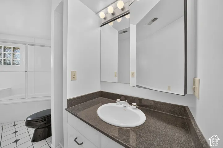 Bathroom vanity featuring a solid surface countertop, integrated oval basin, white cabinetry, a multi-bulb light fixture, and a large mirrored medicine cabinet