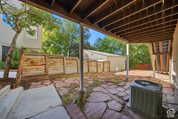 Covered patio featuring flagstone paving, wood-slat perimeter fencing, and structural support posts