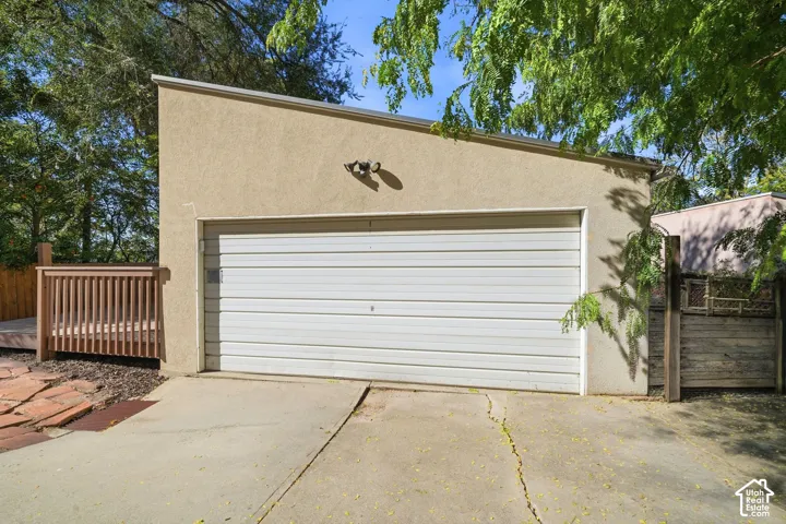 Detached garage with a single-car overhead door, stucco exterior, mono-pitch roofline, and integrated outdoor lighting