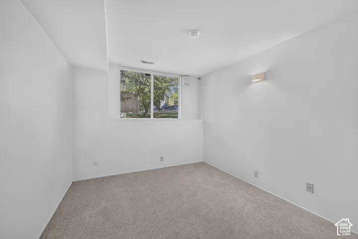 Neutral-toned wall-to-wall carpeting, single-pane window, and wall-mounted sconce lighting