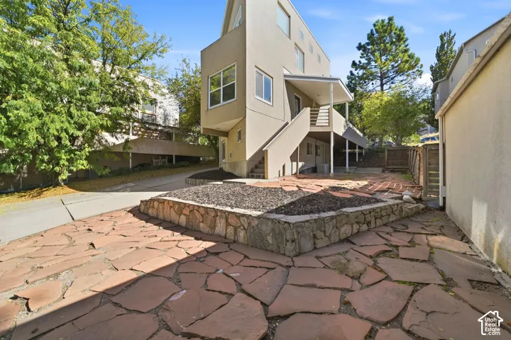 Multi-level structure featuring a flagstone patio, raised stone retaining wall, elevated deck, and staircase access