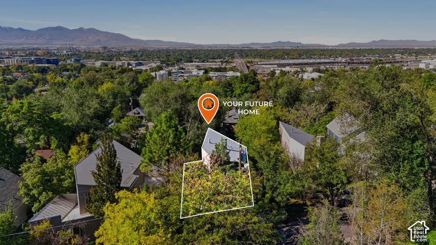 Aerial perspective featuring a residential lot with mature trees and a mountain backdrop