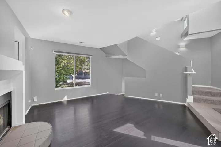 Living area featuring wood-finish flooring, a fireplace with a raised hearth, recessed lighting, and a large window