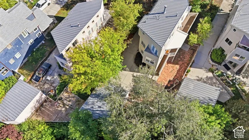 Aerial perspective featuring structures with metal roofing, stone-paved patios, mature trees, and paved driveways