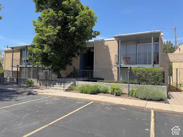 Brick exterior featuring multi-level metal balconies, concrete stairs with metal railings, and a low-profile concrete retaining wall