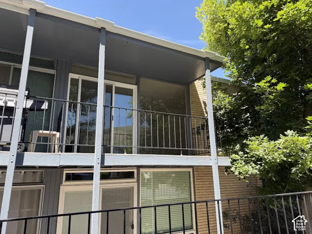 Exterior deck featuring metal railings, brick siding, glass sliding doors, and a covered ceiling