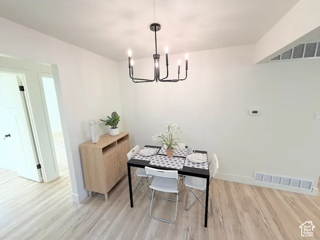 Open-concept area featuring wood-finish flooring and a black six-arm candle-style chandelier