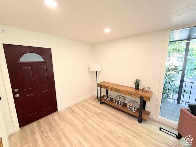 Solid-core entry door with a semi-circular glass insert, light-toned wood-finish flooring, and recessed ceiling lighting