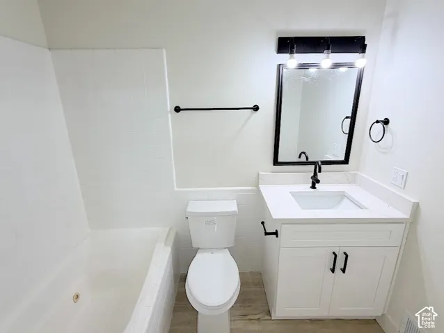 Bathroom featuring white cabinetry, solid-surface countertop with integrated basin, matte black hardware, framed wall mirror, and tub-shower combination with white tile surround
