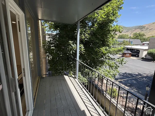 Covered exterior balcony featuring composite decking, metal railings, and a mountain backdrop