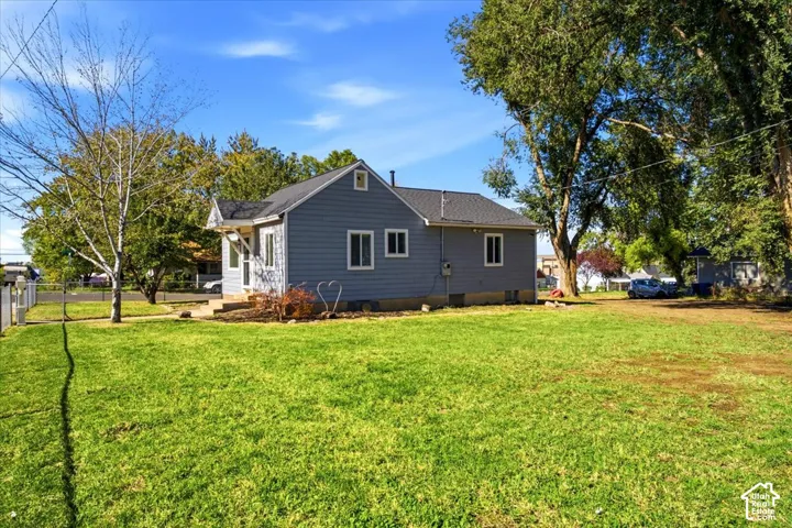 Single-story residence featuring grey lap siding, an asphalt shingle roof, and an expansive lawn with mature trees