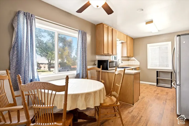 Kitchen featuring wood-finish cabinetry, hard-surface countertops, wood-finish flooring, and a ceiling fan with integrated lighting