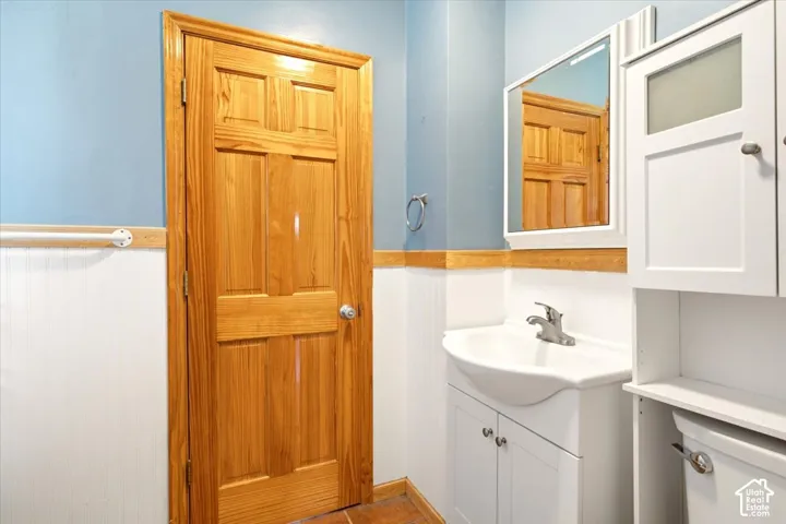 Solid wood six-panel door with matching chair rail, white beadboard wainscoting, vanity cabinet with integrated sink, and white built-in storage cabinetry