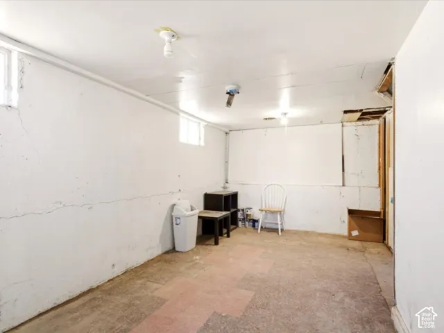 Utility space featuring painted masonry walls, concrete flooring, and two high-positioned windows