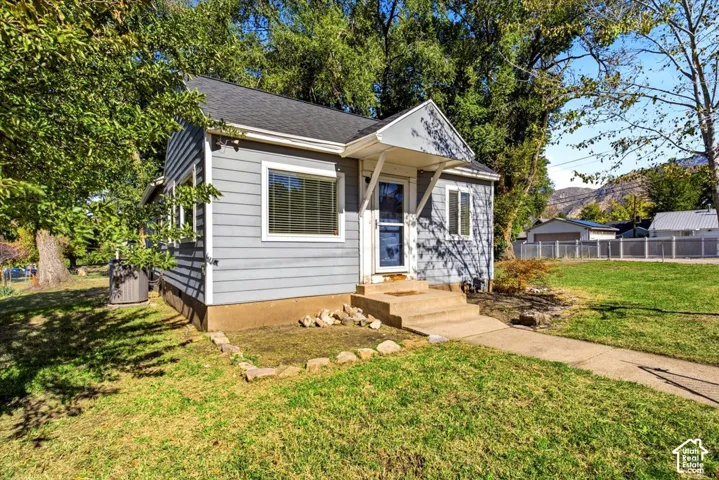 Horizontal siding exterior featuring a gable roof, covered entryway with a metal awning, and concrete front steps