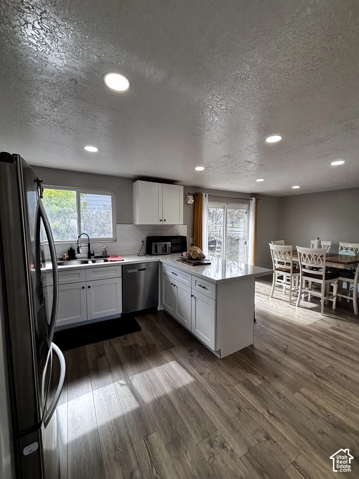 Kitchen featuring white cabinetry, an island with stone-finish countertops, stainless steel appliances, recessed lighting, and wood-finish flooring