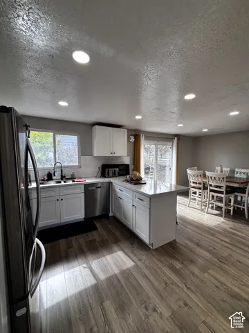 Kitchen featuring white cabinetry, an island with stone-finish countertops, stainless steel appliances, recessed lighting, and wood-finish flooring