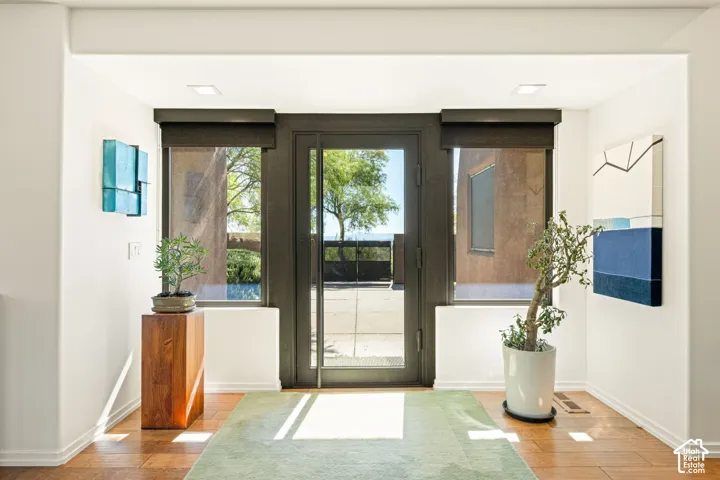 Entryway featuring a floor-to-ceiling glass pivot door, recessed lighting, wood-finish flooring, and flanking tall rectangular windows