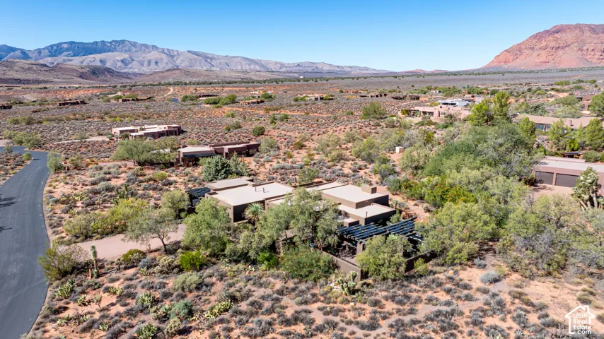 Aerial perspective featuring desert landscape, mountain backdrop, flat-roof architecture, and wooden pergola structure