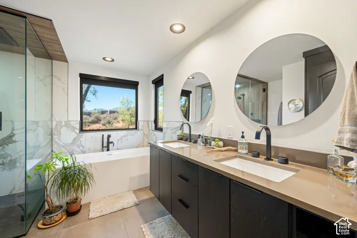 Dual floating vanity with matte black hardware, rectangular undermount sinks, stone-surface countertop, round wall-mounted mirrors, and an enclosed glass shower