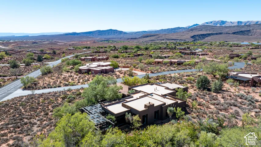 Southwestern-style residence featuring a flat roofline, attached pergola structure, and desert landscaping set against a mountain backdrop