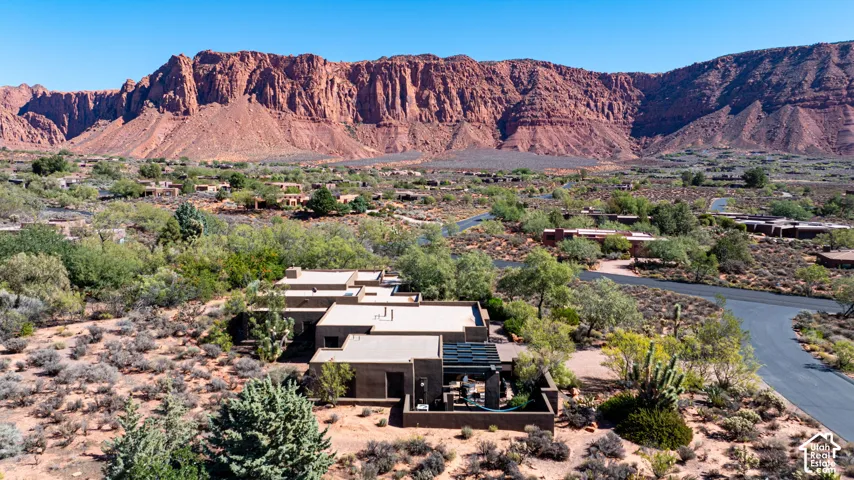 Stucco exterior residence featuring a flat roofline, solar panel array, and desert landscaping set against a prominent mountain backdrop