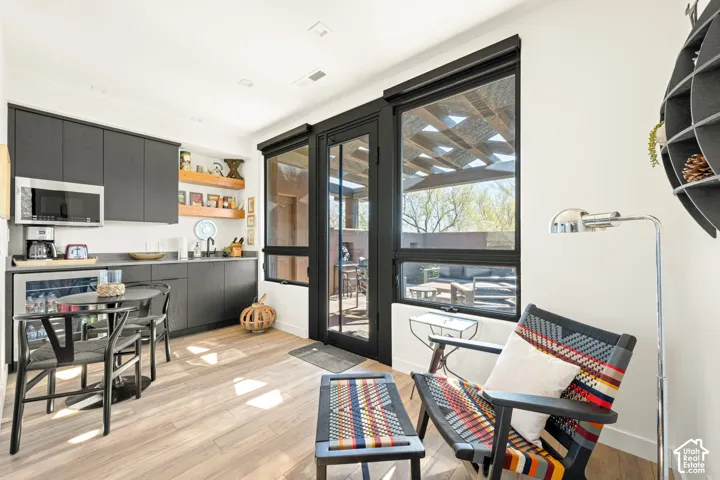 Matte charcoal flat-panel cabinetry, wood-finish flooring, built-in open shelving, and black-framed glass door with matching window casements