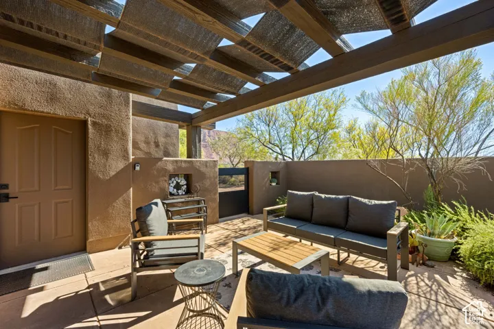 Covered patio featuring a timber-frame pergola, concrete flooring, stucco perimeter walls, and built-in wall niches